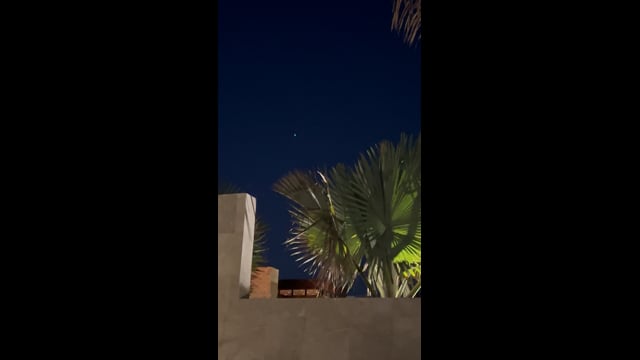 A small light above palm fronds and resort walls in Cabo San Lucas.