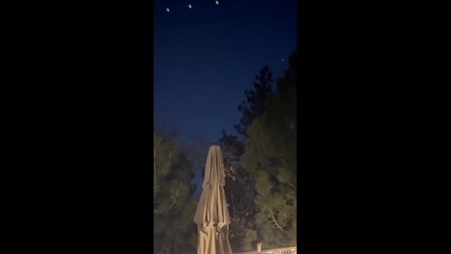 Several small lights above trees and a closed patio umbrella in Big Bear Lake.