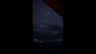 A white light in a clouded sky, viewed beneath a roof overhang in Kauai.