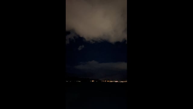 Broad clouds above a dark landscape and distant lights in La Quinta.