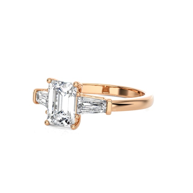 1.00 carat trilogy ring in red gold with a lab grown emerald cut diamond and lab gown tapered baguettes
