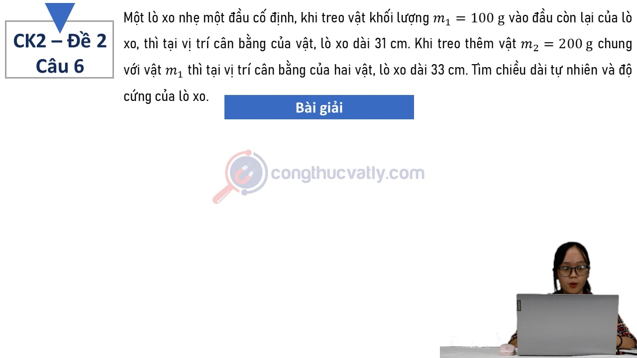 Một lò xo nhẹ một đầu cố định, khi treo vật khối lượng m1 = 100 g vào đầu còn lại của lò xo, thì tại vị trí cân bằng của vật, lò xo dài 31 cm.