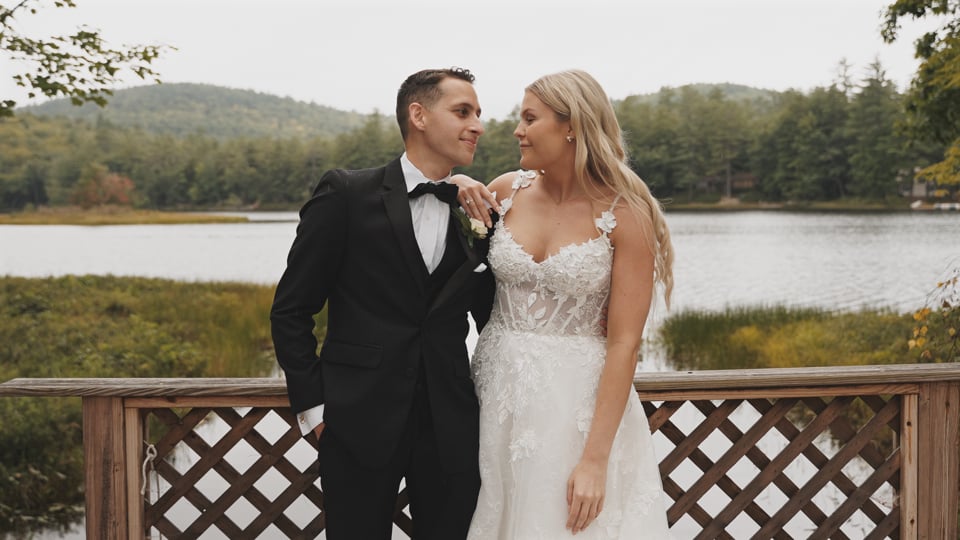 Bride and Groom standing by a lake together for their wedding at Bear Mountain Inn in Waterford, Maine