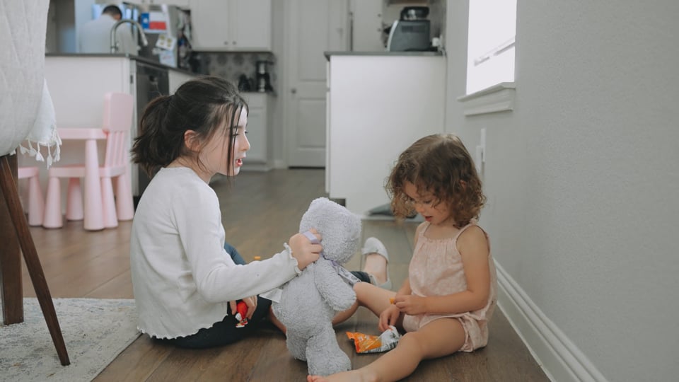 two sisters playing on the kitchen floor