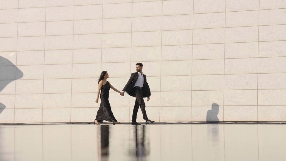 Couple walking hand in hand beside the white walls and reflecting pool at Aga Khan Park, a Happy Soul Films still