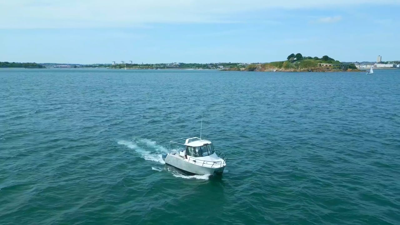 Aerial view of a small white motor boat crossing open water, trailing a wake