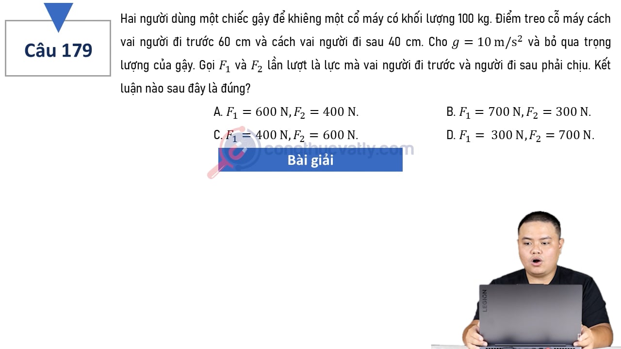 Hai người dùng một chiếc gậy để khiêng một cổ máy có khối lượng 100 kg. Điểm treo cổ máy cách vai người đi trước 60 cm và cách vai người đi sau 40 cm.