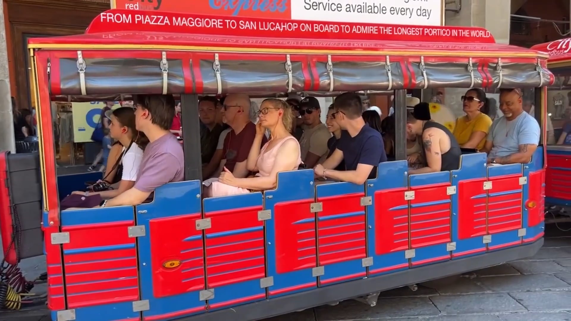 Molti turisti visitano la città a bordo del bus o del trenino di Bologna City redbus