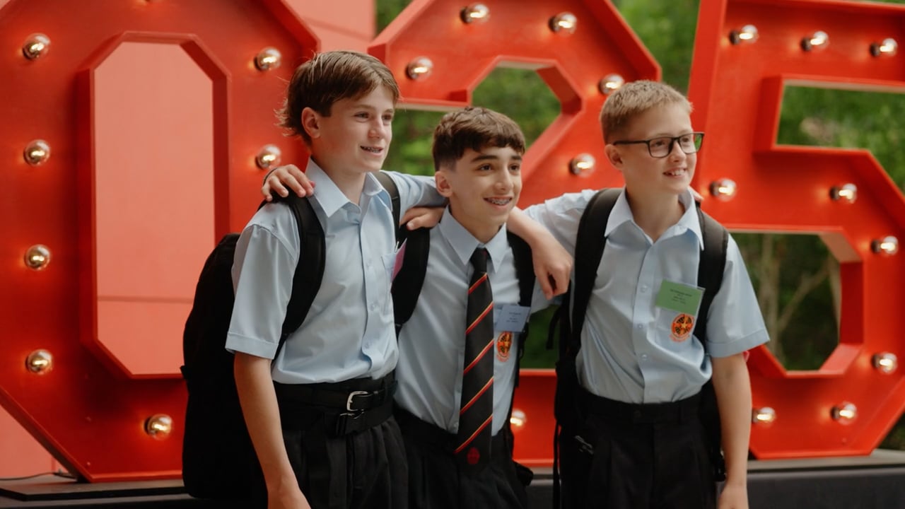 Three students in uniform in front of illuminated ERC letters at Edmund Rice College