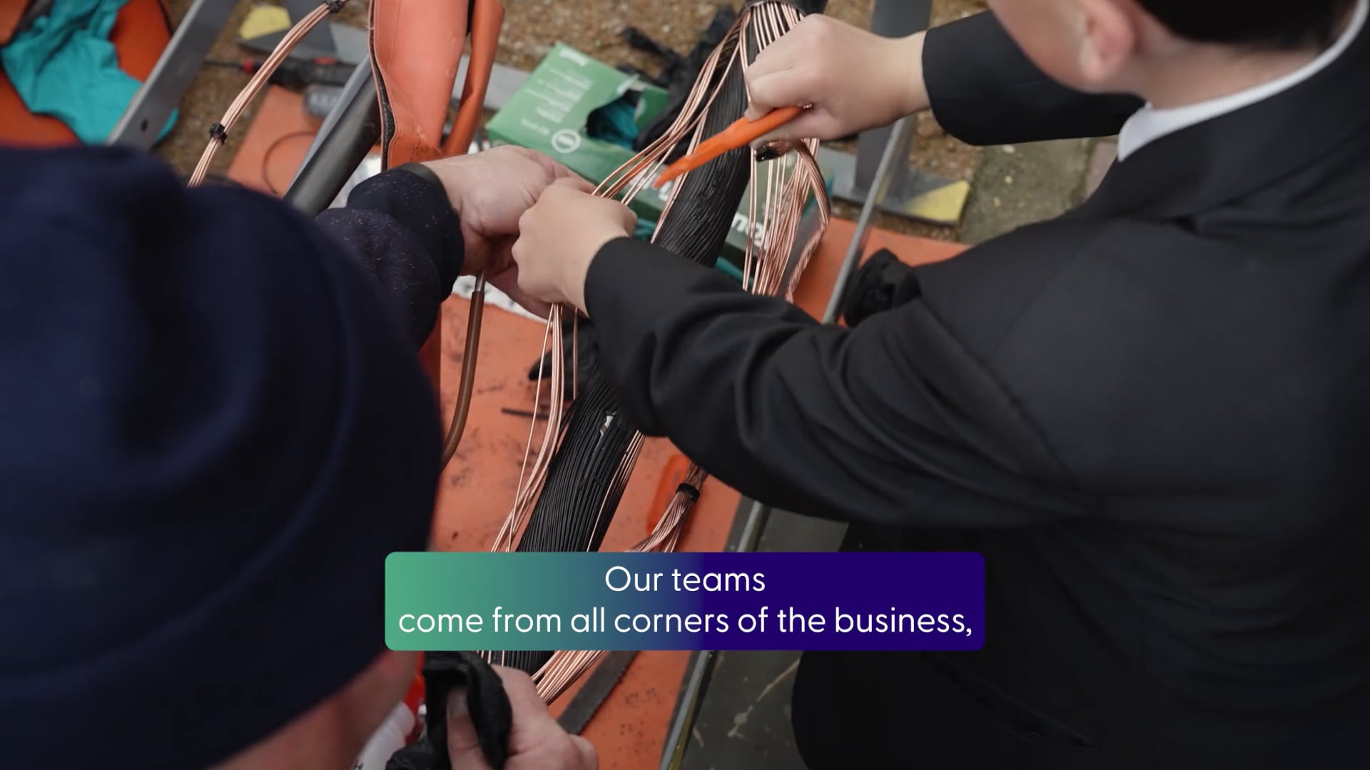 A person in a high vis showing someone in a blue jumper electricity equipment on a display board