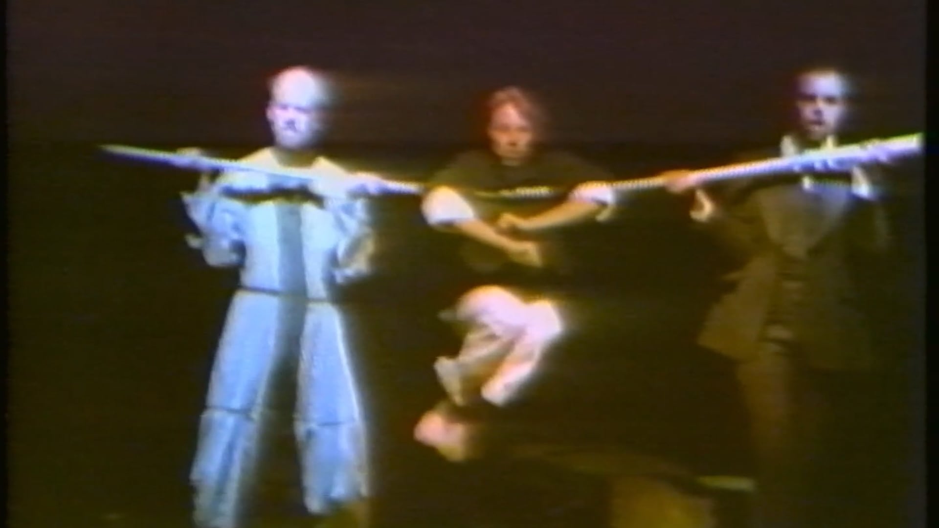 The Way of How premiered at the San Francisco International Theatre Festival in September 1981 and later toured throughout the United States and Europe, including a 1983 presentation in the Brooklyn Academy of Music’s Next Wave series. It was the first work in George Coates’ “How Trilogy,” created with composer Paul Dresher, tenor singers Rinde Eckert and John Duykers, and mime Leonard Pitt.
Described by Coates as a “reverie,” the performance followed four distinct figures as they explored an environment of tubes, poles, hoops, mirrors, hand trucks, and other elemental objects. The performers transformed these materials into musical instruments, sculptural forms, and visual events: tubes became pitched percussion instruments, hoops became horns, and two descending poles appeared to carry the singers’ voices into the mime’s body. The work used operatic excerpts, musical games, monologues—including a “To B” sequence of composers whose names begin with B—and live vocal looping. Its scenes centered on discovery, tentative alliances, and the changing relationships among performers, objects, sound, and space.