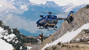 Air rescue helicopter hovering over a snowy mountain ridge during aerial filming