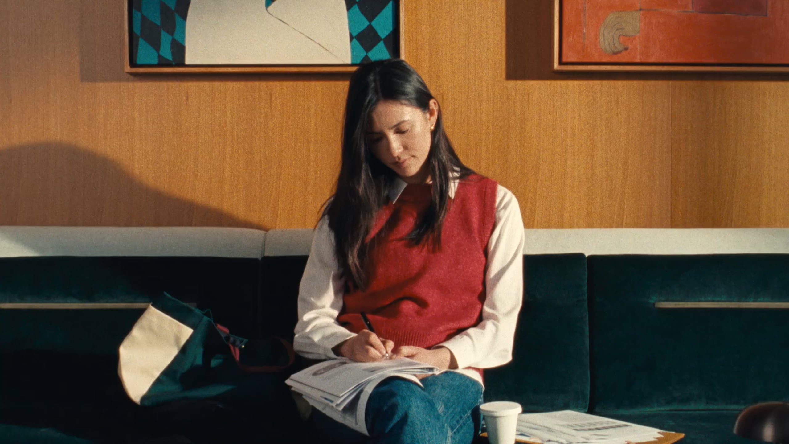 A resident reading on a green banquette below framed artwork