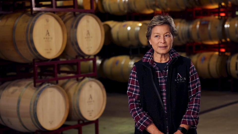 Woman standing among oak wine barrels at Andis Wines