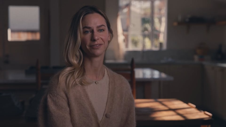 Woman standing in a softly lit kitchen, testimonial-style video