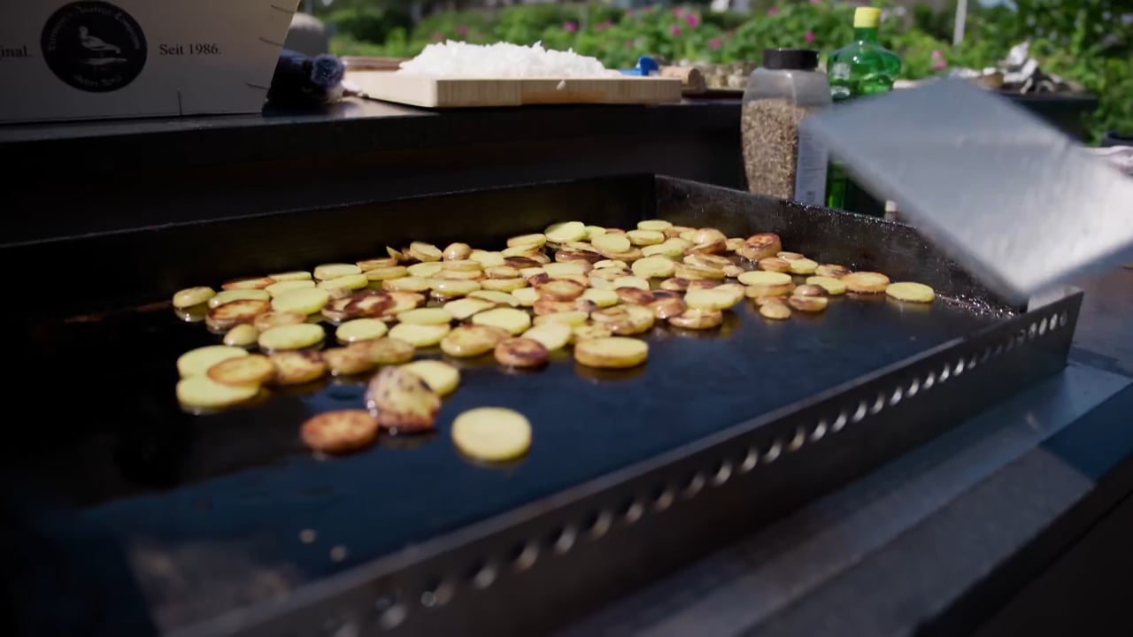 Kartoffelscheiben auf der Plancha wenden, Streetfood auf Sylt