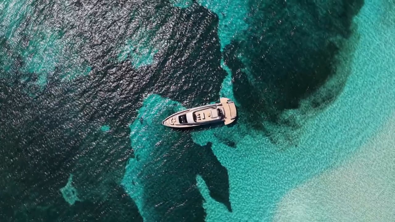 Overhead aerial of a Pershing motor yacht over clear turquoise water