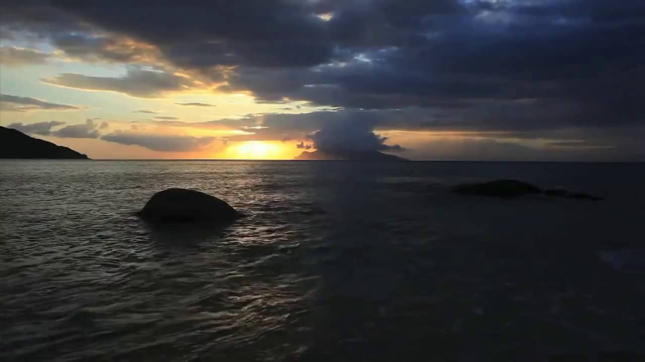  An image of a sunset over the ocean with large waves crashing on the shore and dark clouds overhead with the search query, 'High-quality audio equipment with large drivers, noise cancellation, and high-resolution audio codec support.'