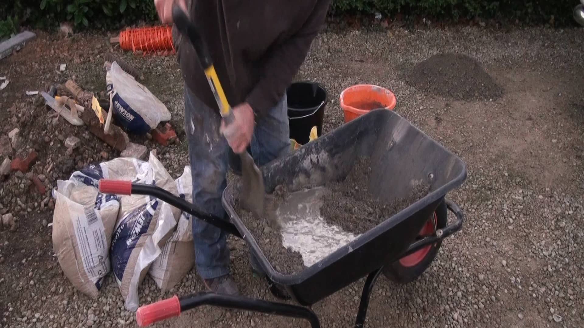 Mixing concrete in a wheelbarrow for edging stones or garden paths on Vimeo