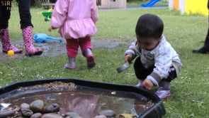 Toddler explores natural materials & sound outdoors thumbnail