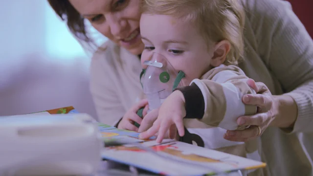 Niñito en una máscara, tratamientos del tracto respiratorio con un  nebulizador en casa. El bebé se sienta con un nebulizador en su boca,  inhalador, tratamiento de bronquitis Fotografía de stock - Alamy