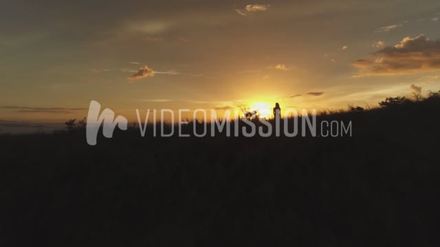 Drone Flying Over Ridge Past Woman At Sunrise