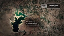 Satellite image of Lake Buchanan. A gray box in the top right corner has text that reads "Lake Buchanan, Texas, USA." To its left is a light gray box that has the year "2011" in it. Text toward the bottom reads "A "bathtub ring" of exposed lakebed shows around Lake Buchanan."