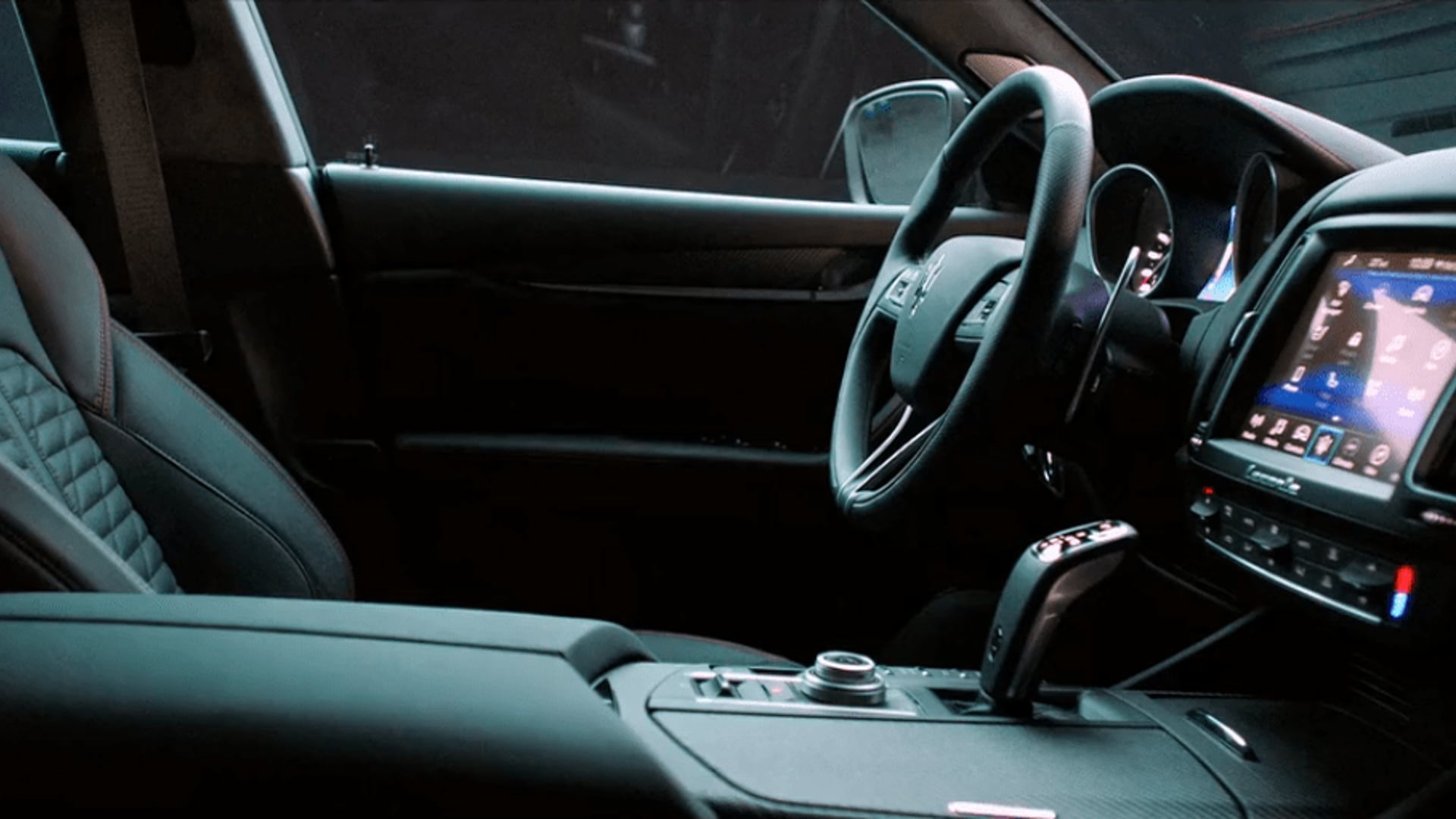 Inside the Maserati Levante Trofeo: the steering wheel, gear selector and lit display in a dark cabin