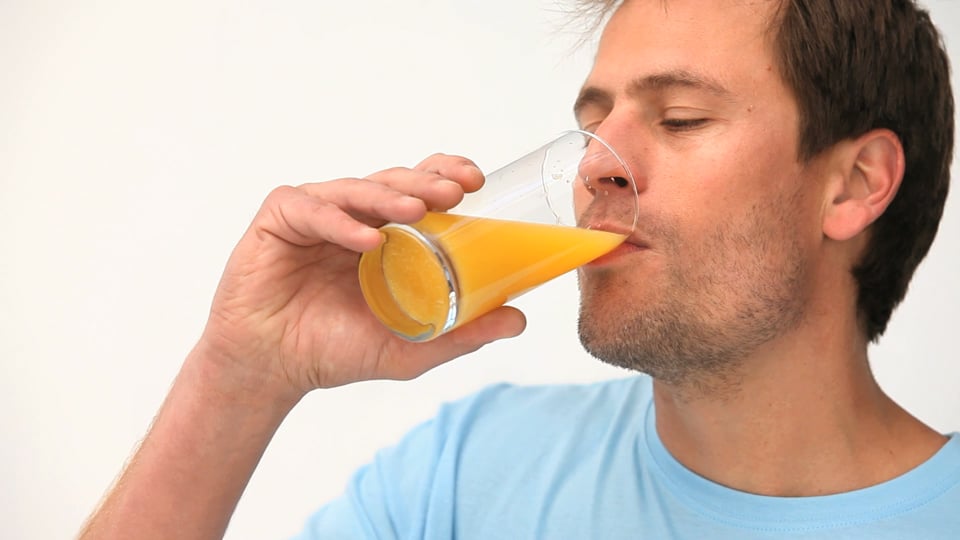 мужчина апельсиновый сок. мужчина с соком. парень пьет сок. коктейль в руках мужчины. мужчина пьет сок.