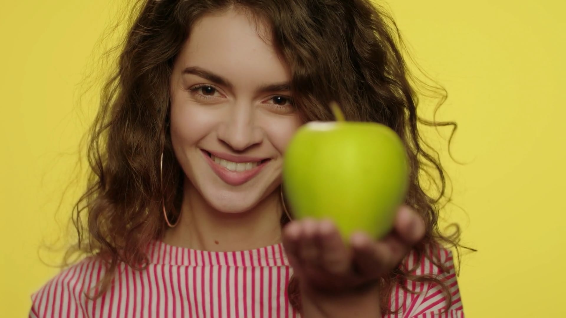 videoblocks-young-woman-weighing-apple-and-cake-in-hands-in-yellow ...